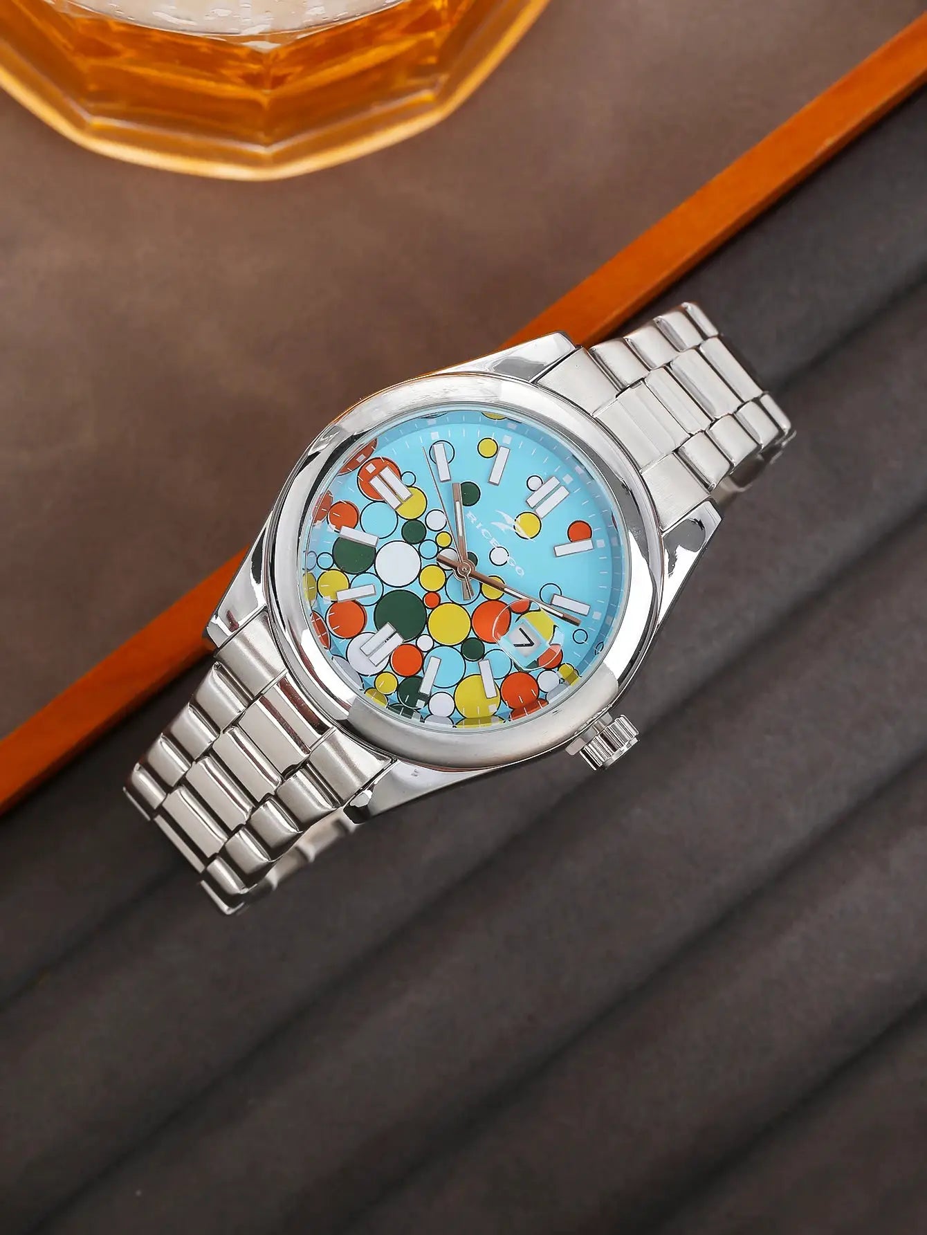 Men's stainless steel quartz watch with blue dial featuring multicolored circles, date window, metal bracelet.