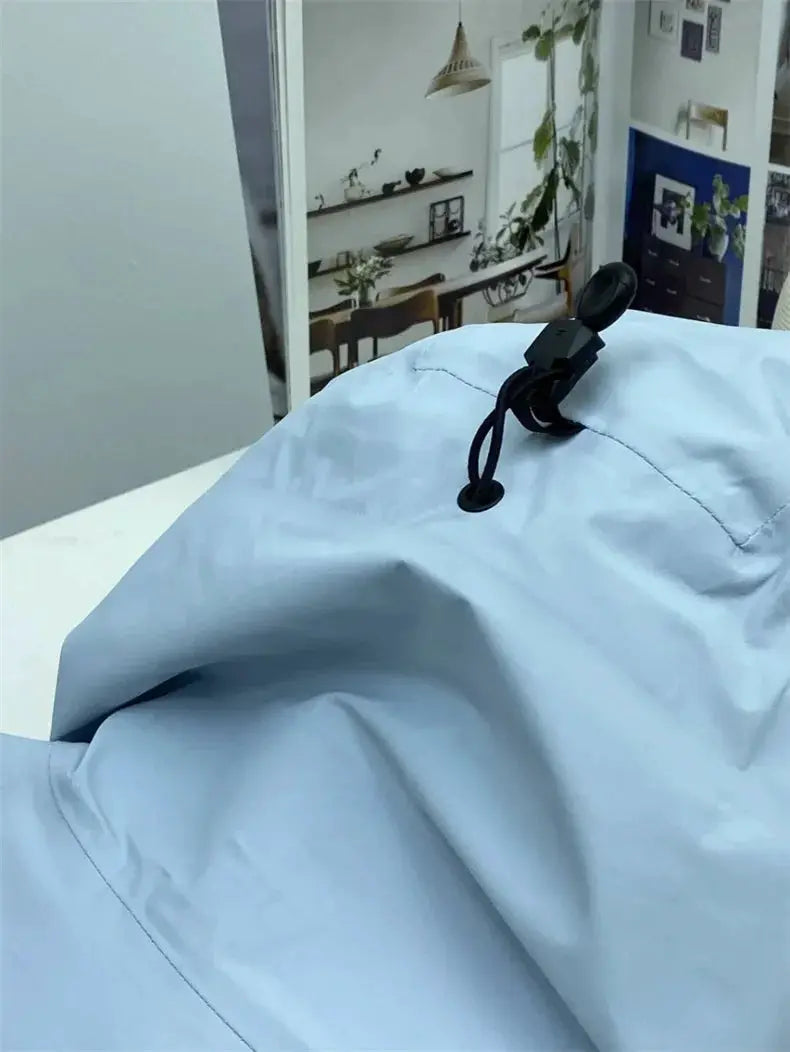 Light blue outdoor windproof soft shell jacket with black drawcord toggle