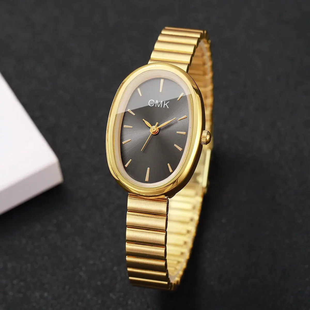 Women's CMK gold-toned oval-dial analog quartz watch with a metal link bracelet.