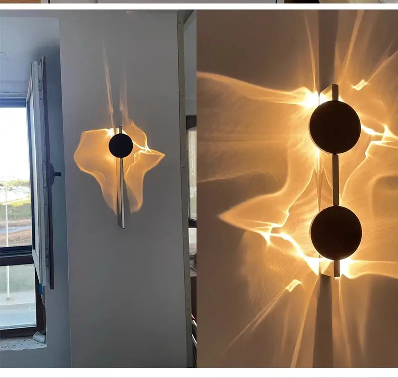 Modern LED wall light with rotatable stainless steel bar and two black circular discs, warm ambient glow.