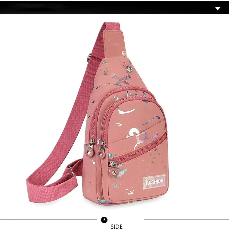 Pink chest bag crossbody sling with paint-splatter print and multiple zip pockets, pink adjustable strap.