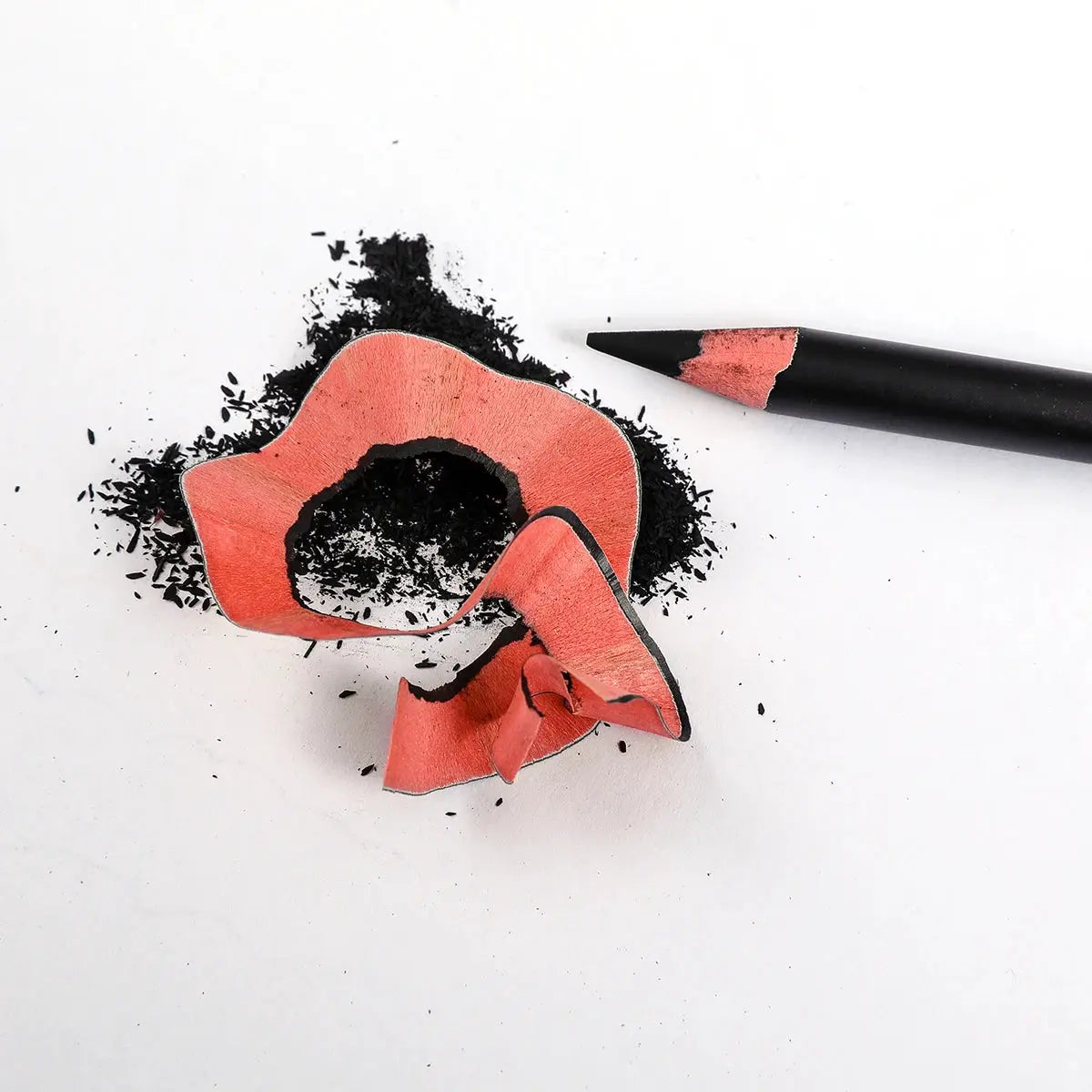 Charcoal pencils with pink wood and scattered black dust