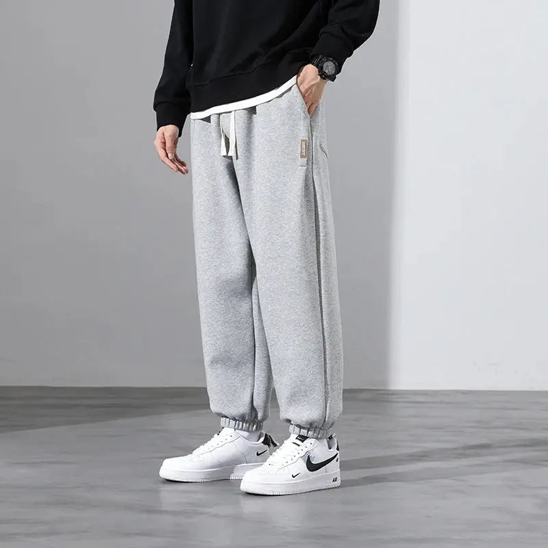 Men's grey loose-fit drawstring jogger sweatpants and white Nike sneakers