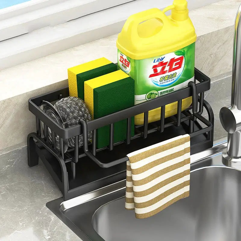 Black kitchen sink drain rack with two sponges, scrubber, Liby bottle, and striped towel