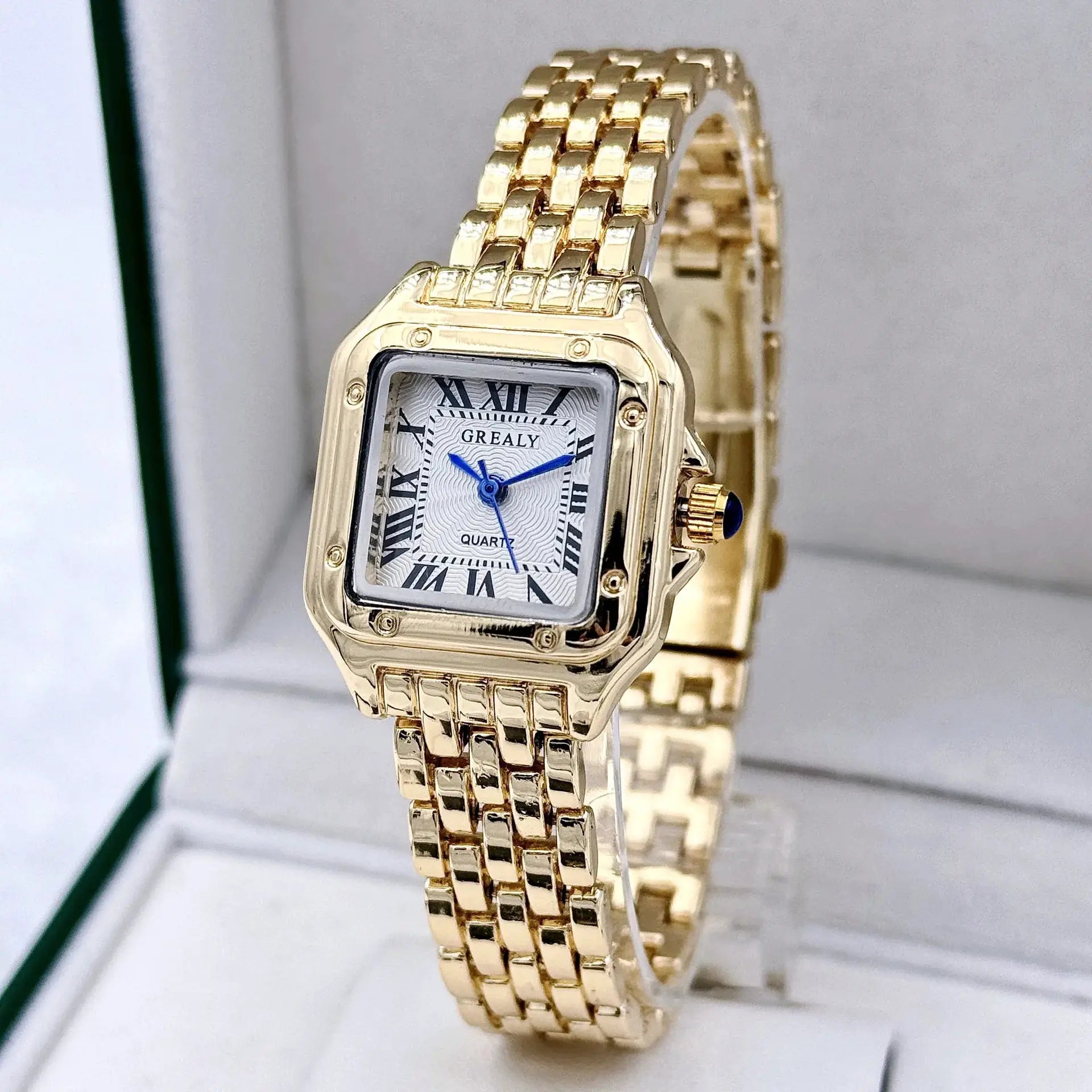 Gold-tone stainless steel women's wristwatch with square case, Roman numerals, blue hands, quartz movement, and link bracelet