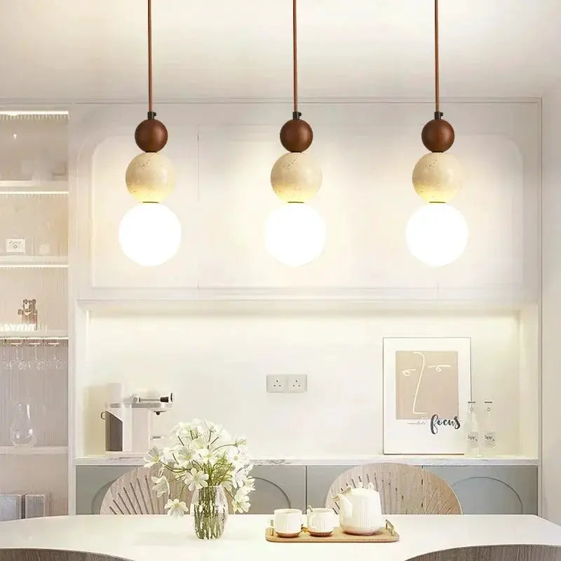 Cream style pendant lamp trio with stone-and-wood beads above a white dining table