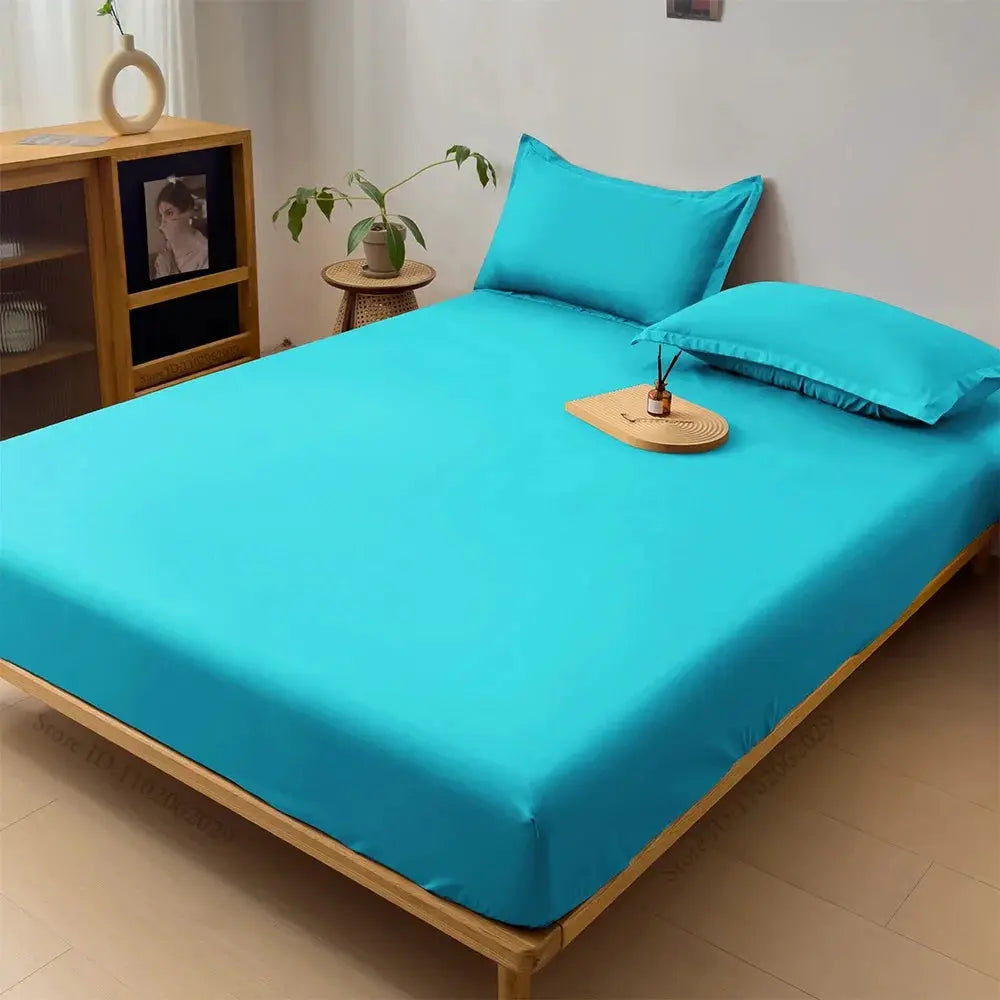 Turquoise waterproof fitted mattress cover on a wooden bed with two matching pillows