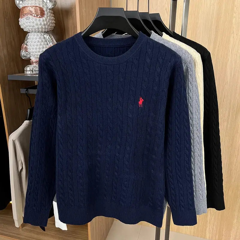Men's navy cable-knit sweater with round neck and red polo embroidery; six-color knitwear display on rack.