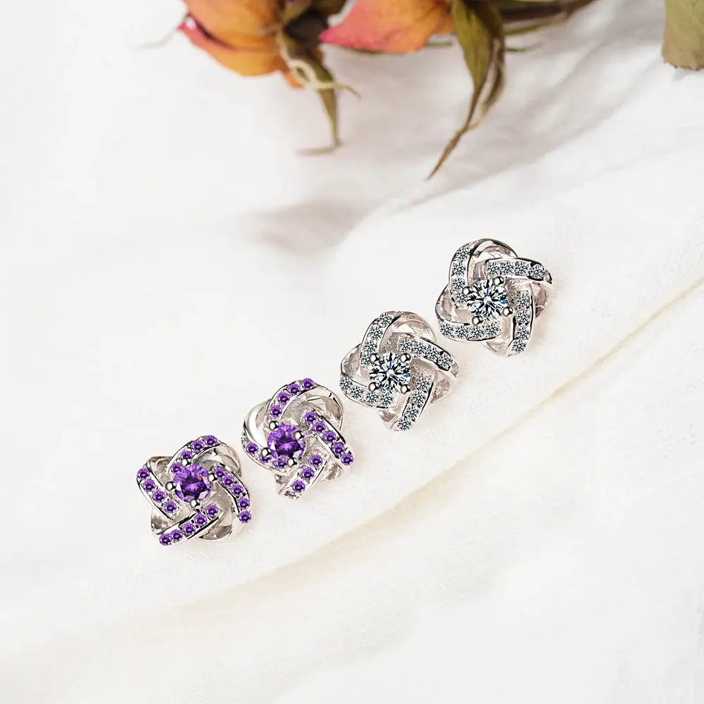 Five sterling silver earrings featuring purple and clear zirconia in a twist knot design.