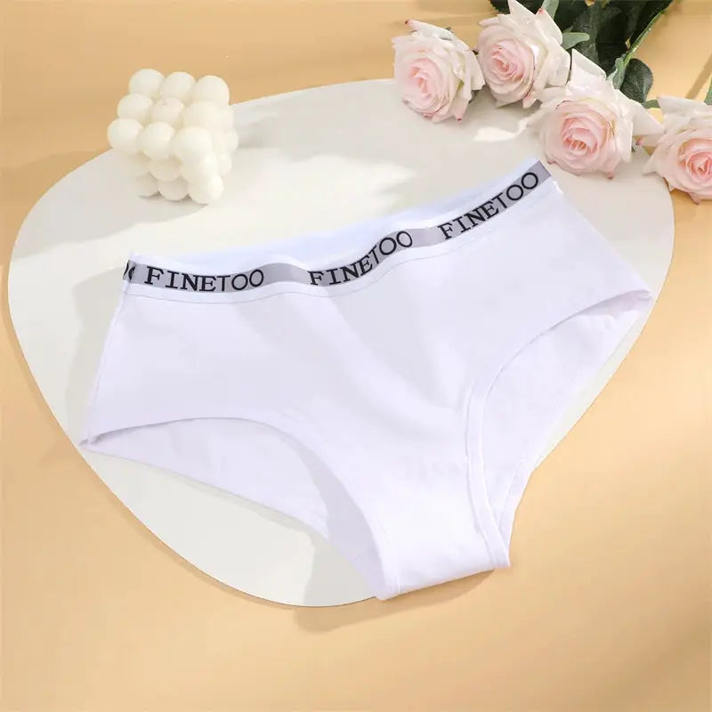 White cotton women's briefs with Finetoo waistband, breathable underwear on a round table.