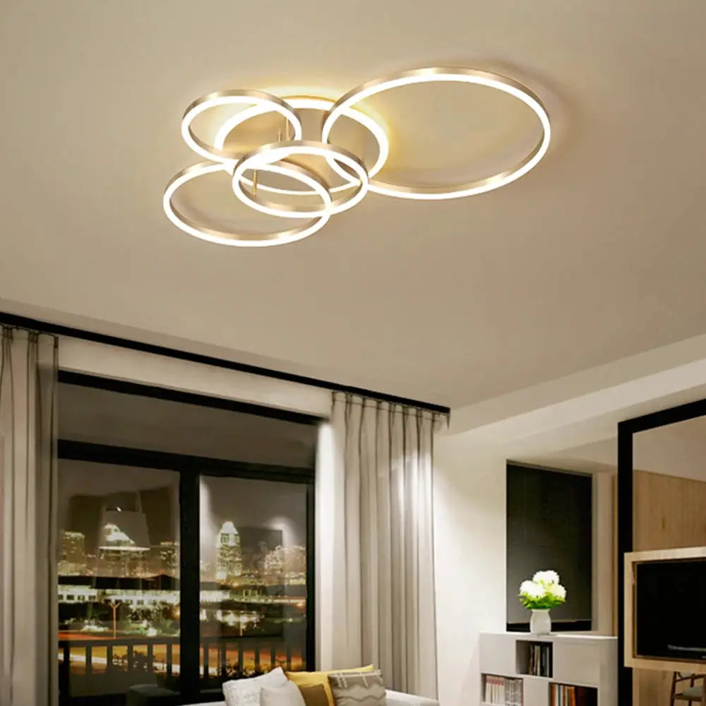 Modern LED ceiling chandelier with interlinked circular metal rings emitting dimmable warm white light.