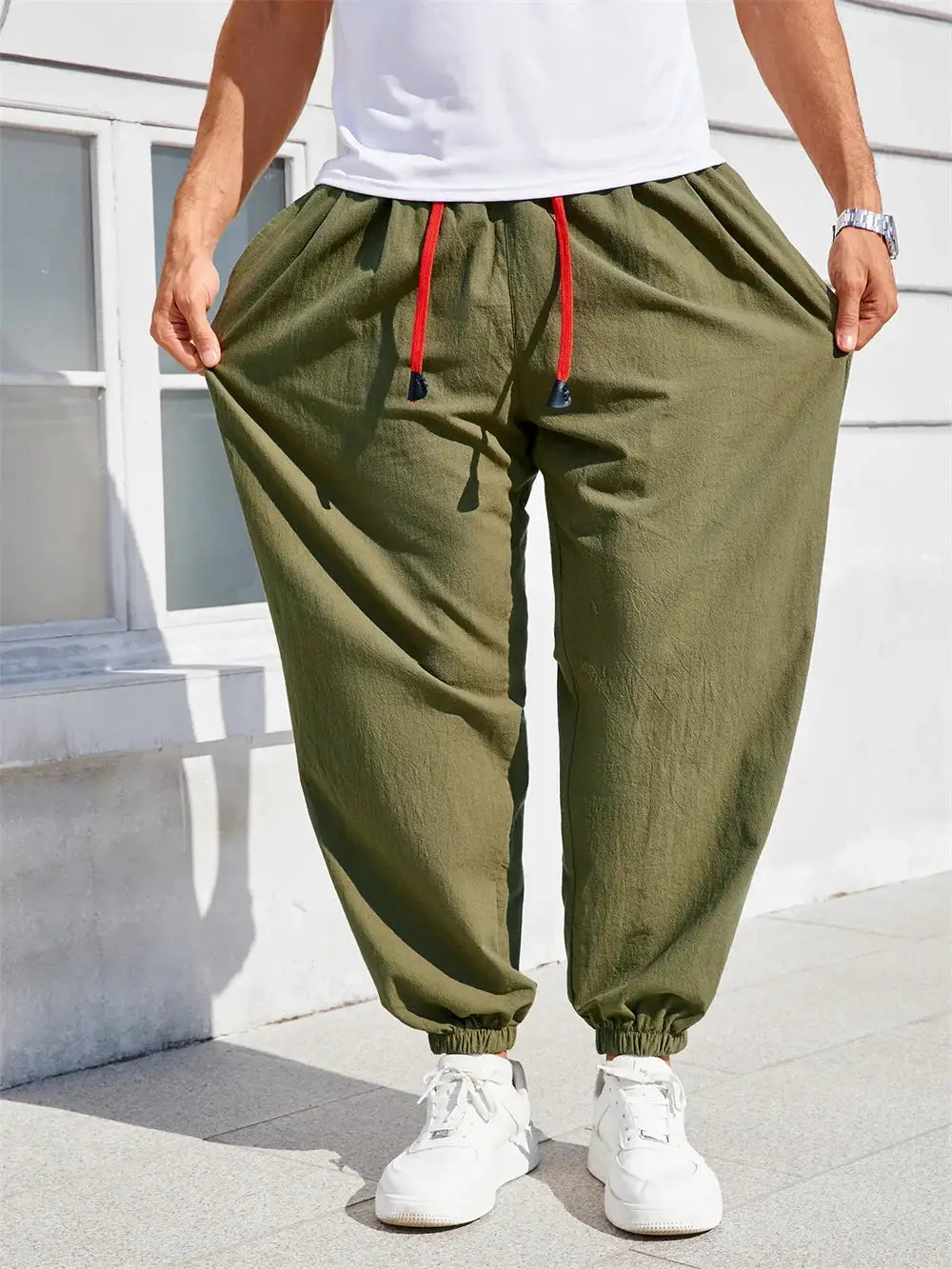 Men's loose-fit harem pants in olive cotton-linen with red drawstring and cuffed ankles, casual joggers