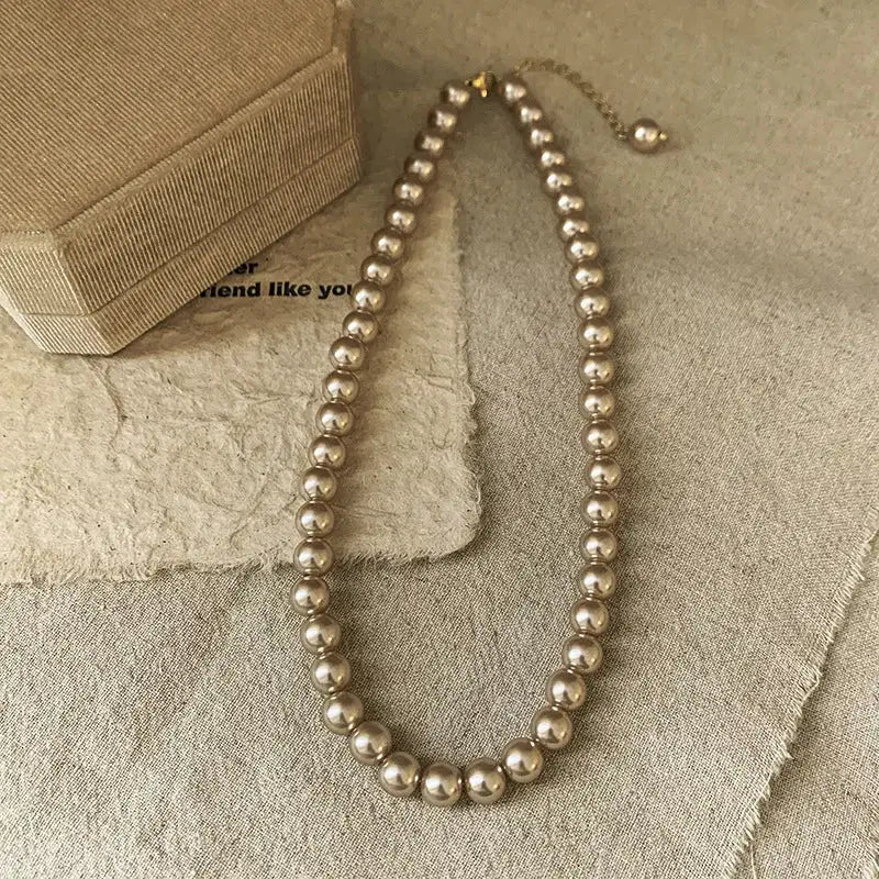 Imitation pearl necklace with cream beads, collarbone-length, adjustable chain.