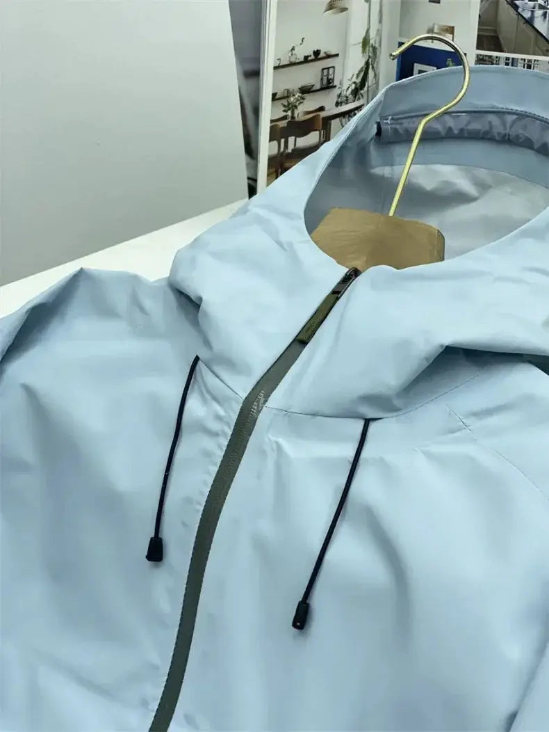 Outdoor jacket for men by Simples Market, light-blue windproof soft-shell with hood, zipper and drawstrings.