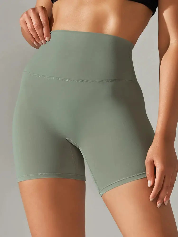 Women's high-waist sage green yoga shorts with smooth, stretchy fabric.