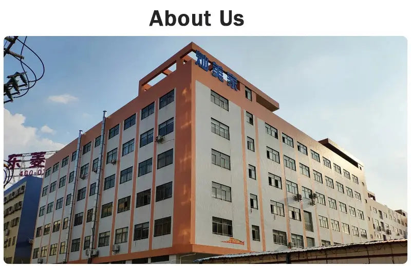 Factory exterior: large multi-story building with orange trim and many windows under a blue sky on a sunny day.