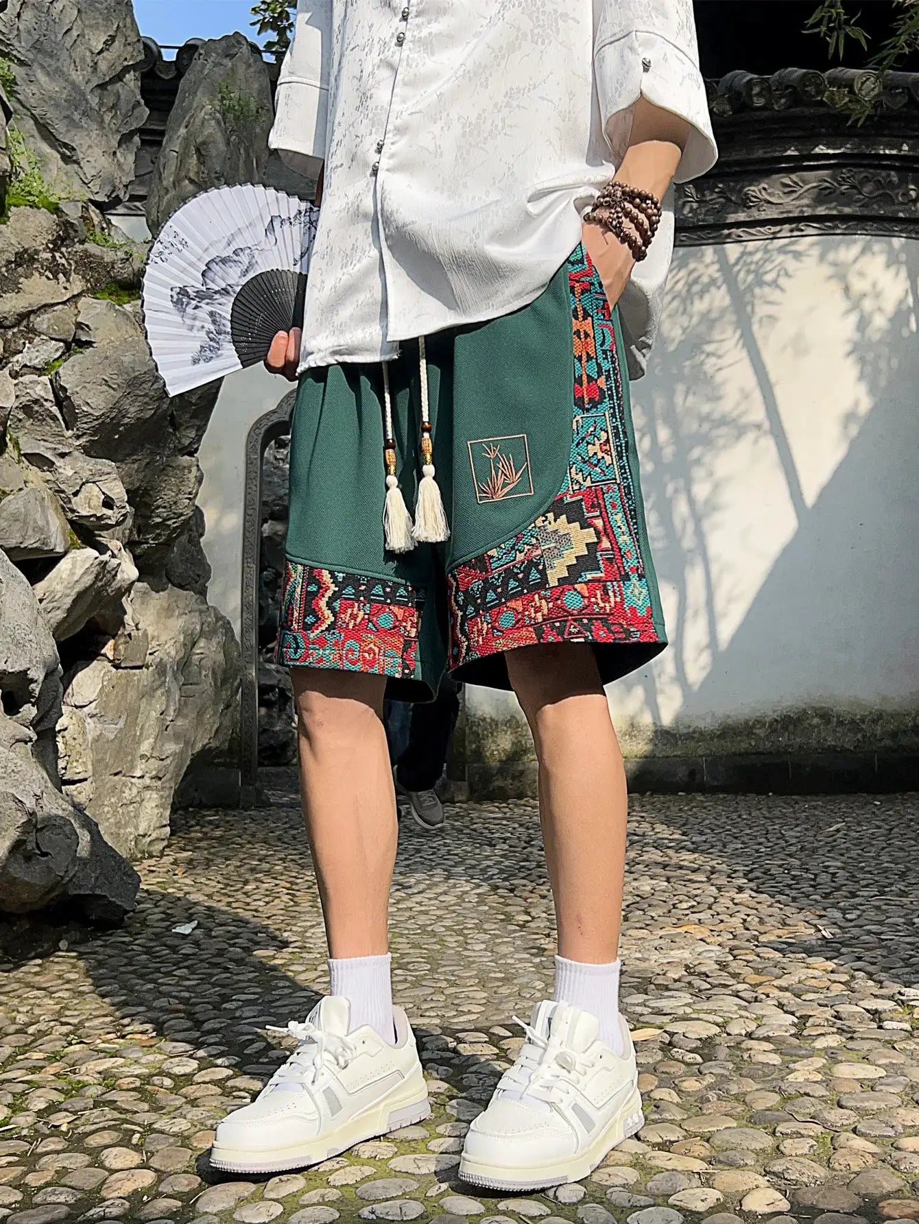 Men's green ethnic embroidery shorts with pockets and colorful patterned trim, drawstring waist.