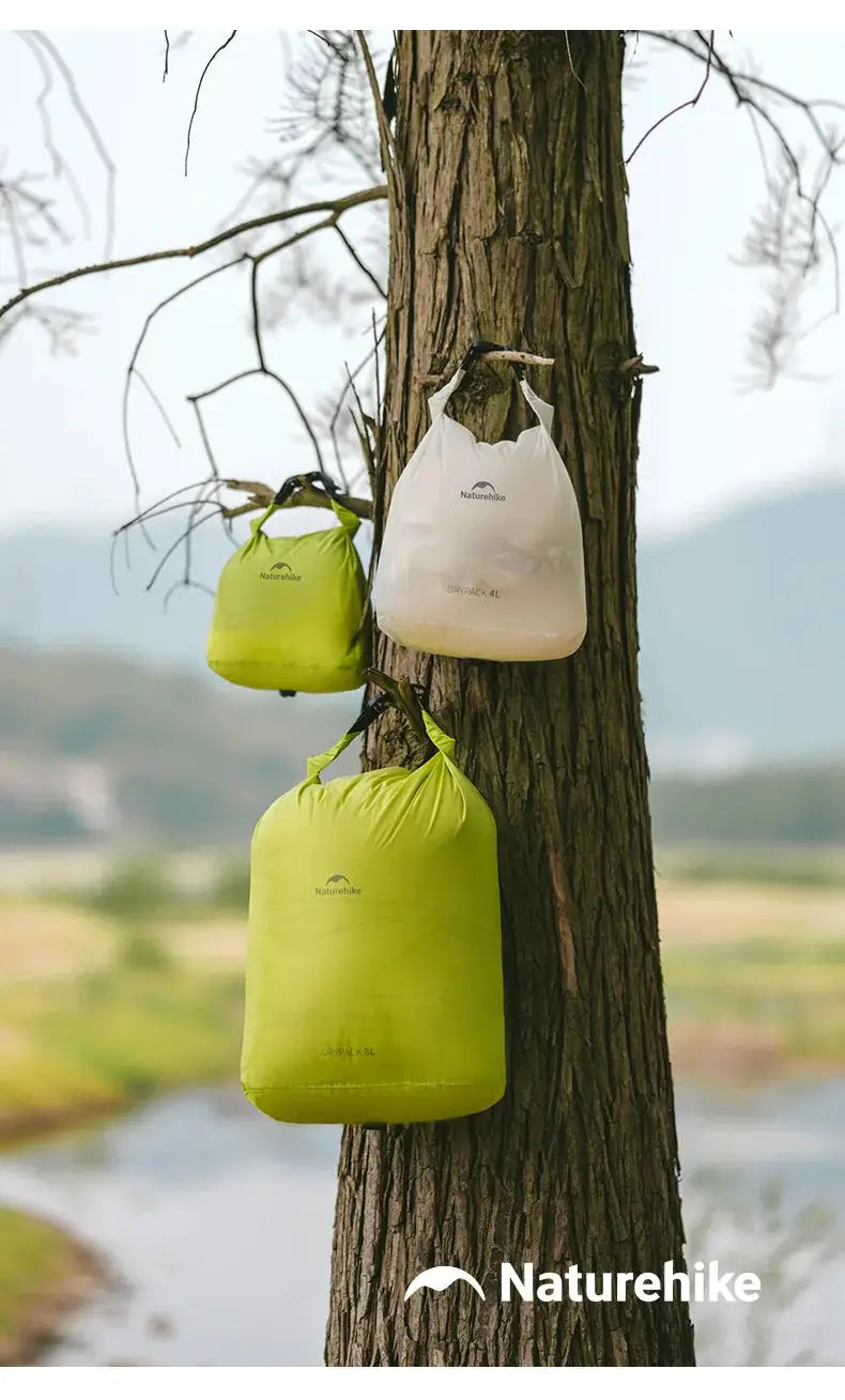 Naturehike rolled storage bags (3) in lime green and white, hanging from a tree; lightweight waterproof vacuum organizers