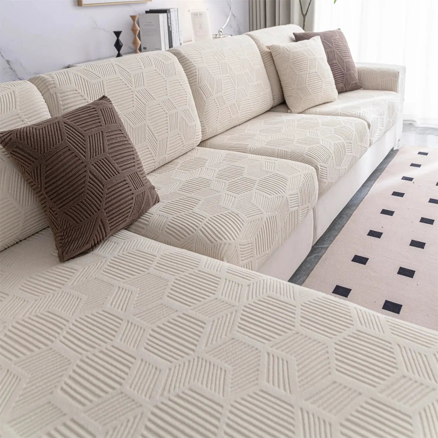 Beige jacquard stretch sofa cover with matching cushion covers on a living room sofa, brown accent pillows