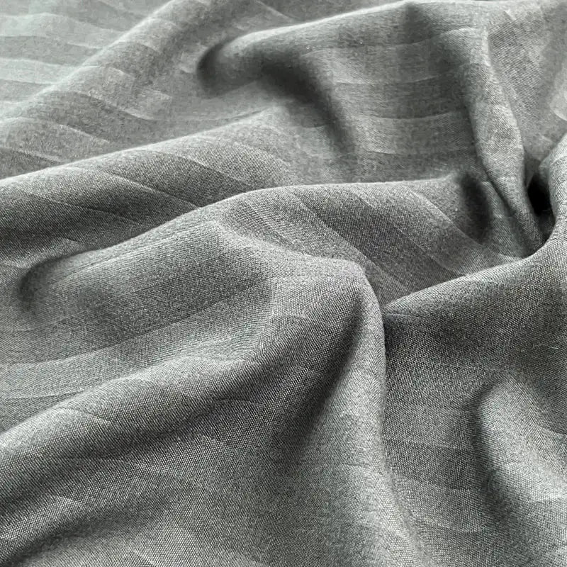 Gray fitted bed sheet with elastic band, soft solid-color fabric.