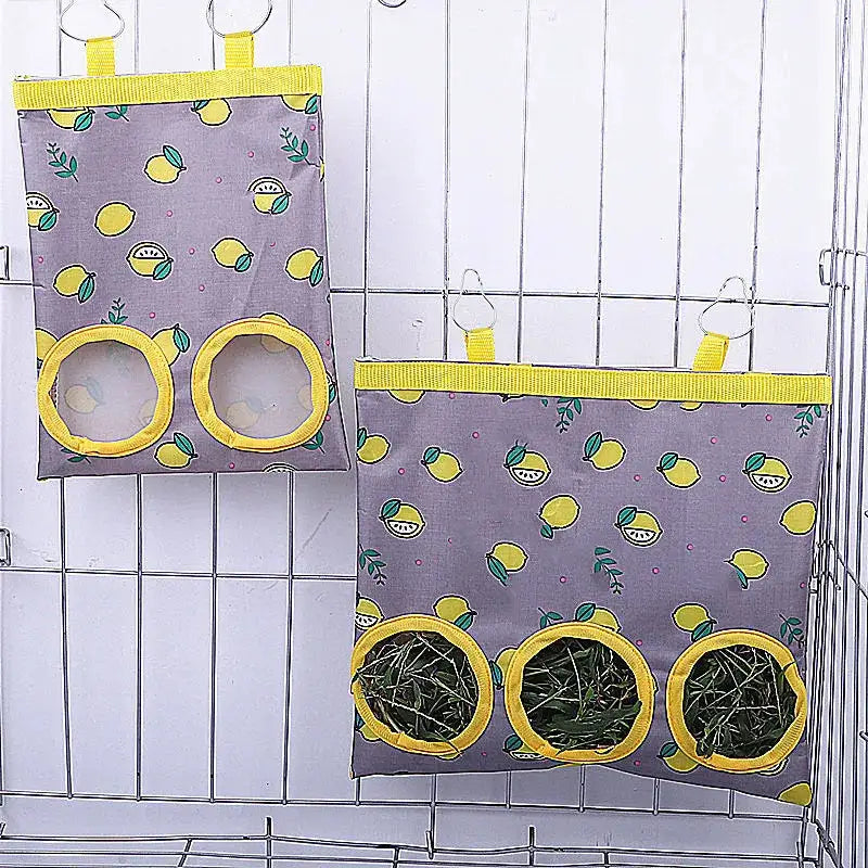 Two rabbit hay bags with yellow trim and lemon pattern, hanging in a cage; 2-hole and 3-hole grass feeders.