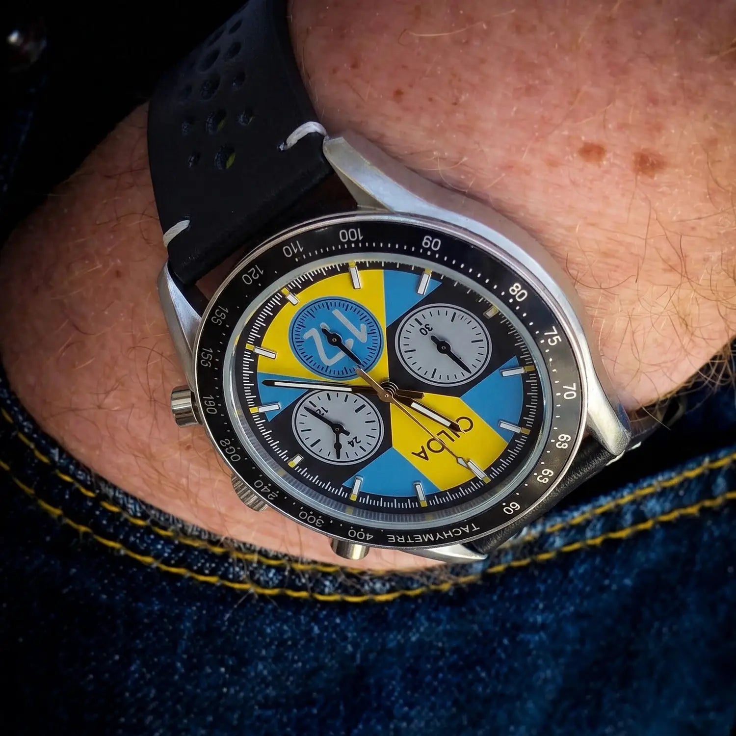 CILOA men's racing chronograph watch with blue and yellow dial, black perforated leather strap, tachymeter bezel.