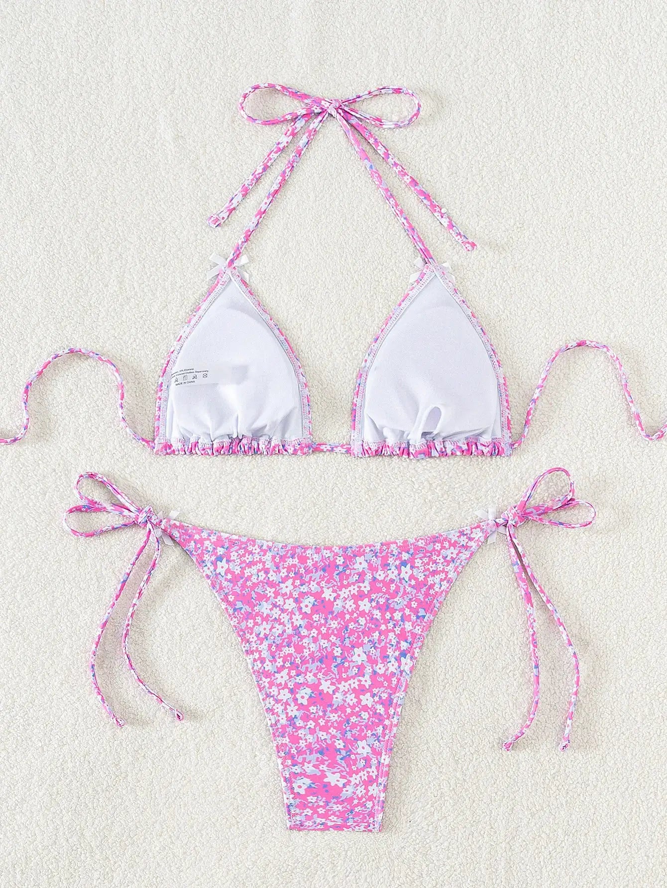 Two-piece bikini set by Simples Market; pink floral bottoms with side ties and white top with pink trim.