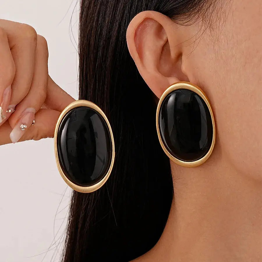 Large oval black resin earrings with gold-tone border; Simples Market pair.