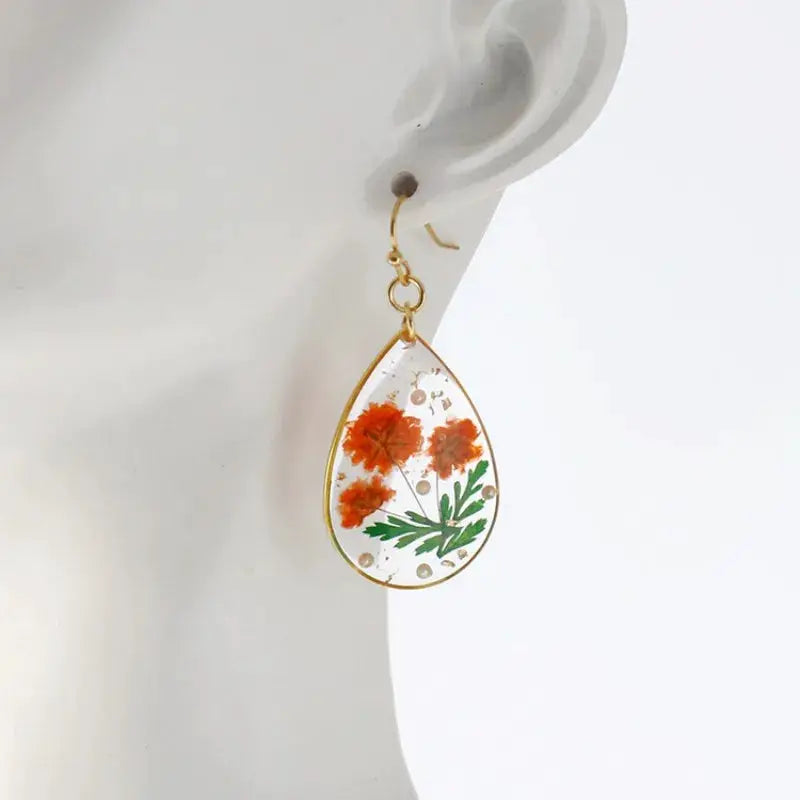 Colorful natural flower teardrop resin earrings with orange blooms, green leaves, gold frame
