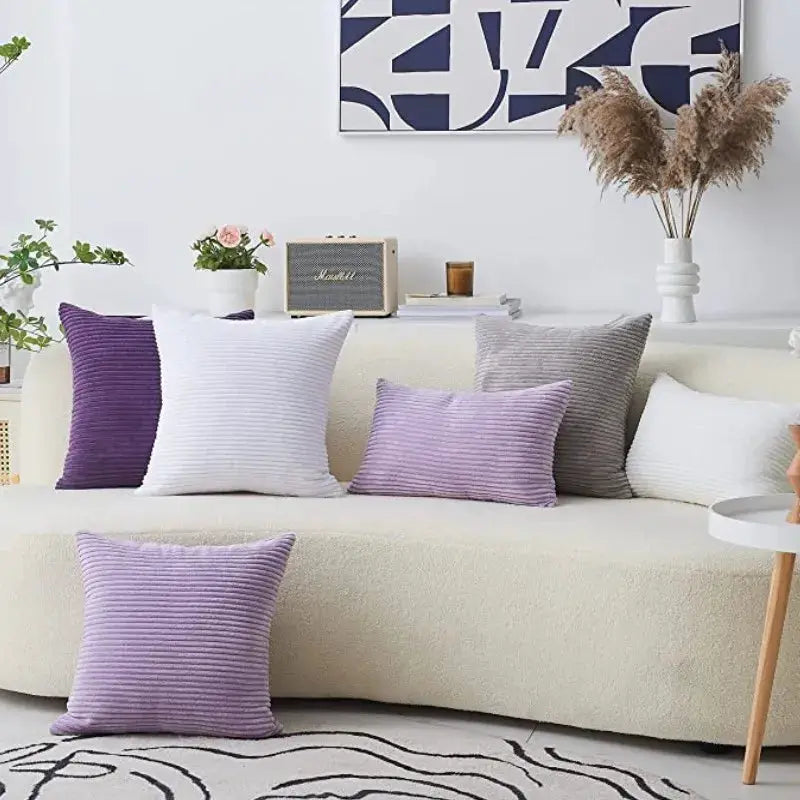 Six corduroy striped pillow covers in lilac and purple on a cream sofa for modern living room decor