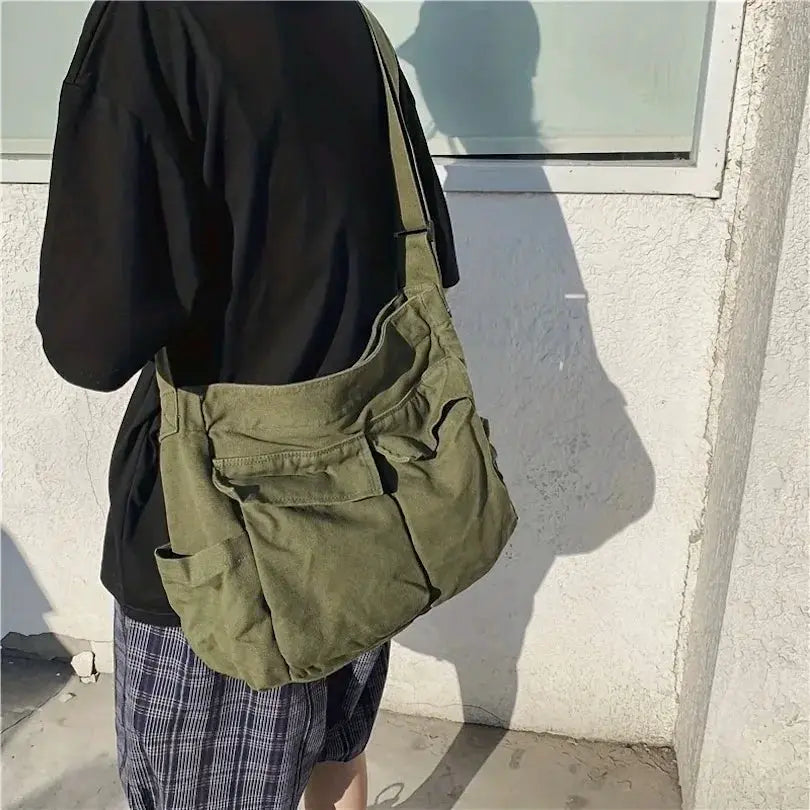 Olive green canvas women's messenger bag with multiple front pockets and large capacity, worn as a shoulder crossbody