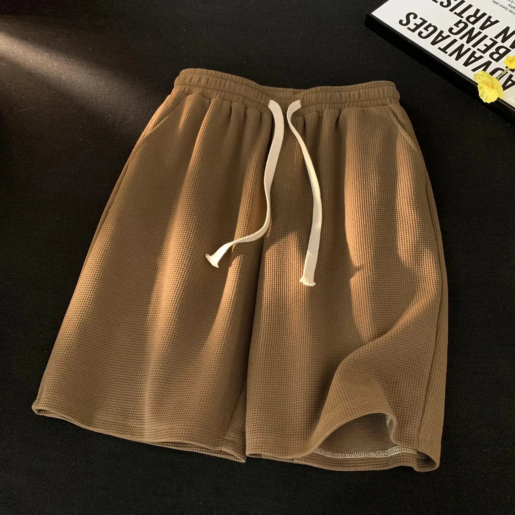Waffle shorts for men, tan waffle-knit fabric with white drawstring; lightweight, loose summer wear.