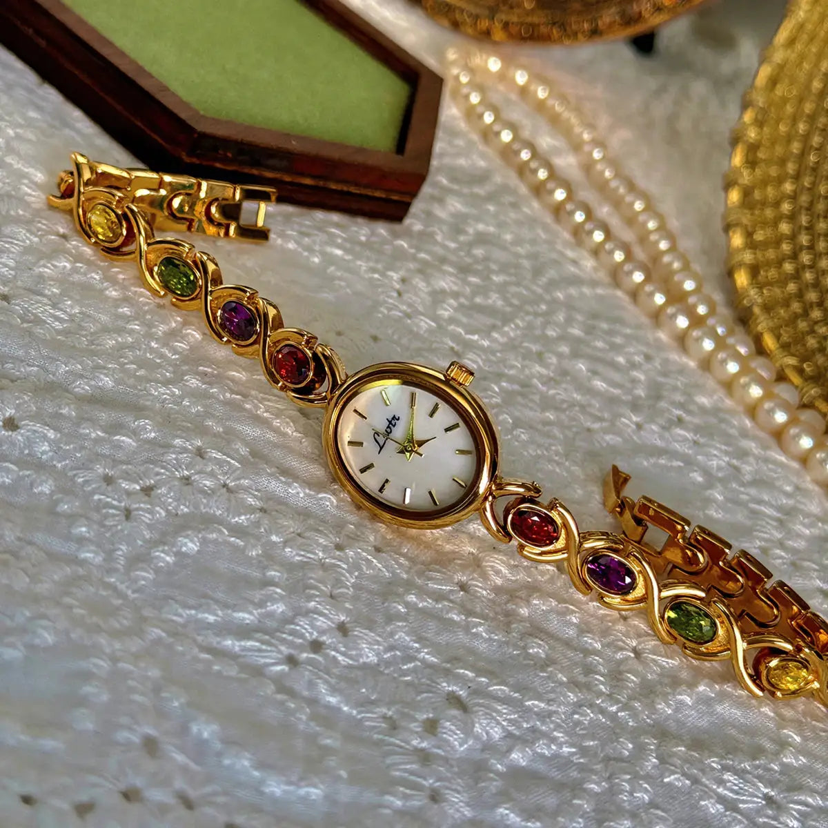 Gold-tone women's watch from Simples Market with oval mother-of-pearl dial and rainbow tourmaline stones.