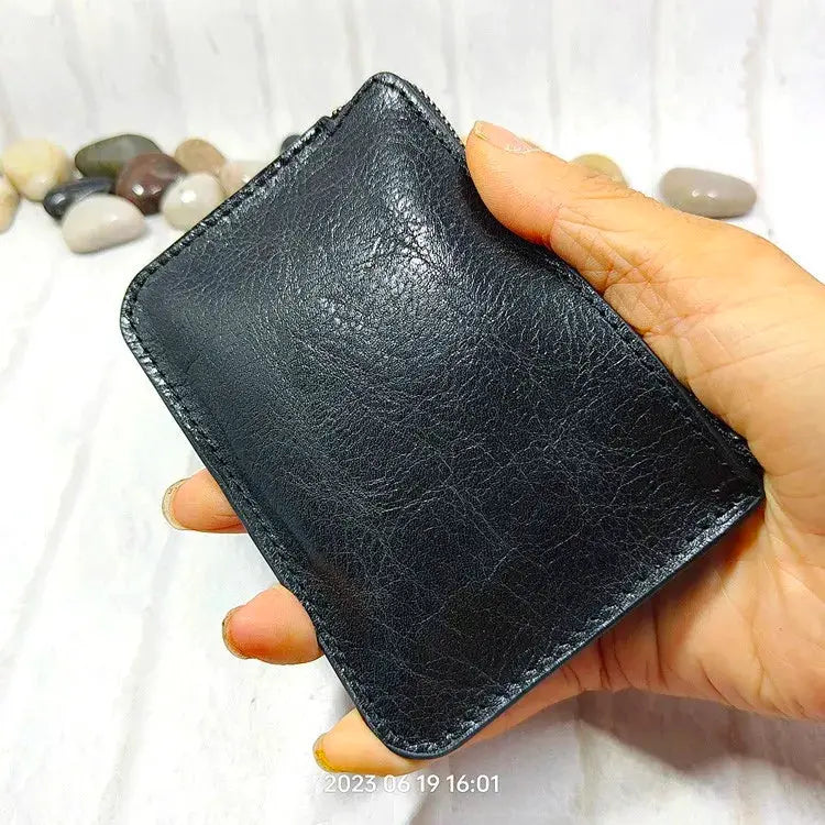 Mini black leather zipper wallet card holder held in hand