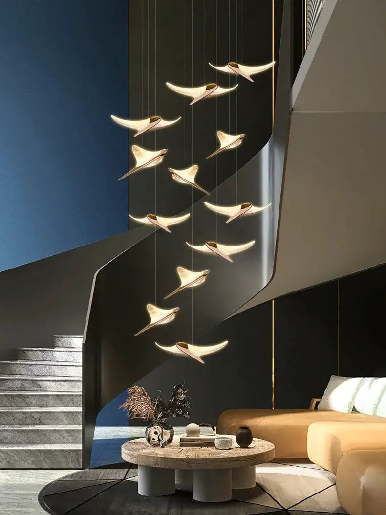 Seagull staircase pendant lamps, modern gold-toned hanging light sculptures along a curved stairwell in a duplex lobby