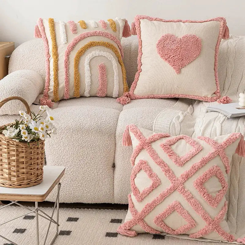 Pink cotton tufted pillow cover with tassels on a cream sofa with decorative cushions.