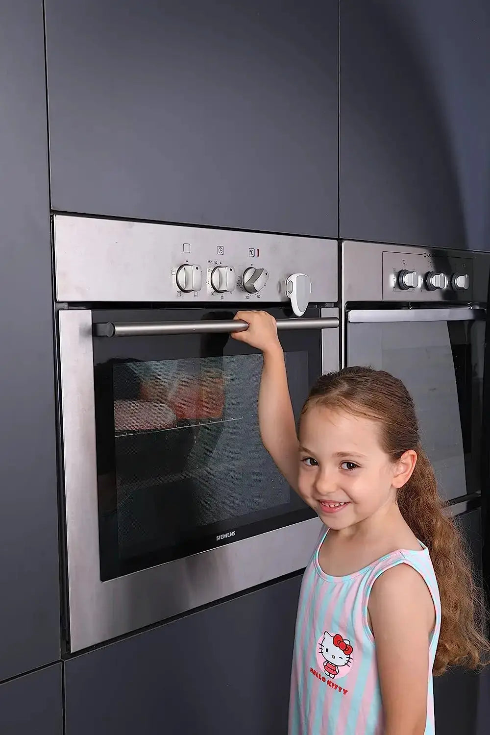 Baby oven door lock for kitchen safety; stainless steel oven with a smiling child nearby