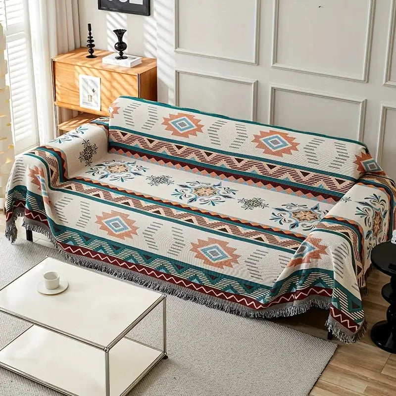 Ethnic patterned sofa cover on a living room sofa; teal, rust and ivory geometric design with fringe.