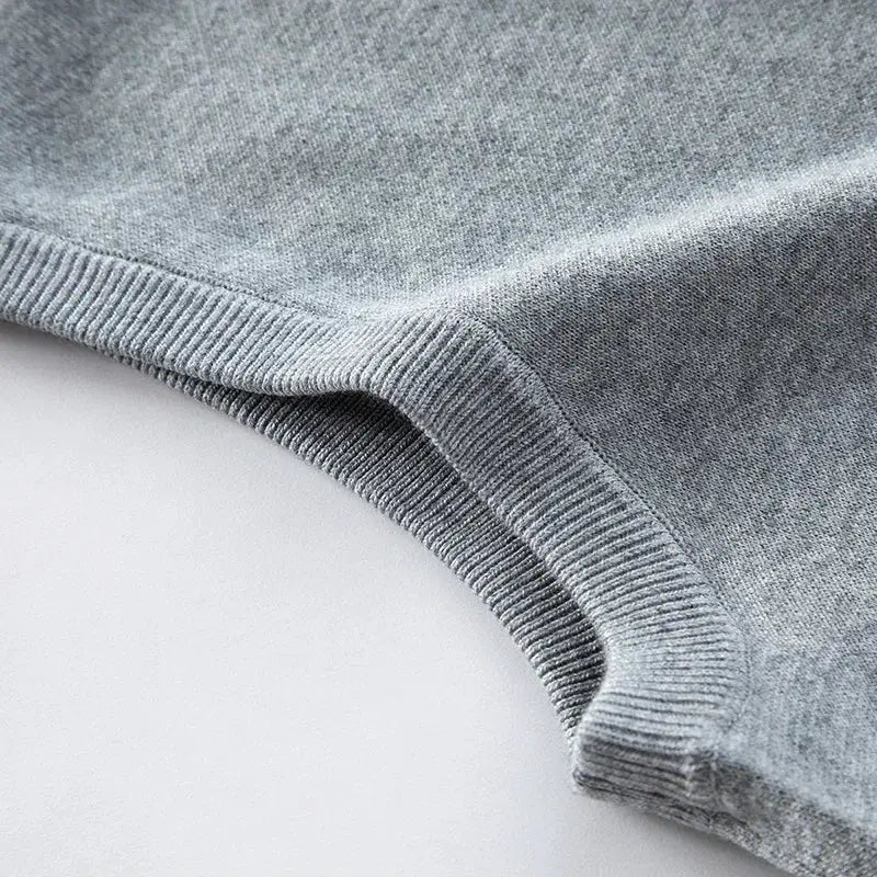 Grey knitted sweater fabric close-up with ribbed cuff