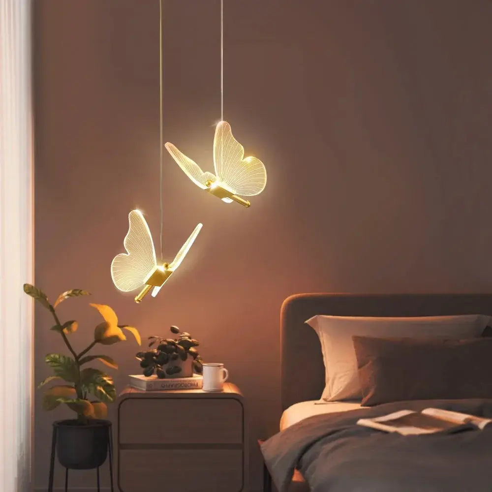 LED modern butterfly pendant lights, two warm-white butterfly fixtures hanging over a bedside table.