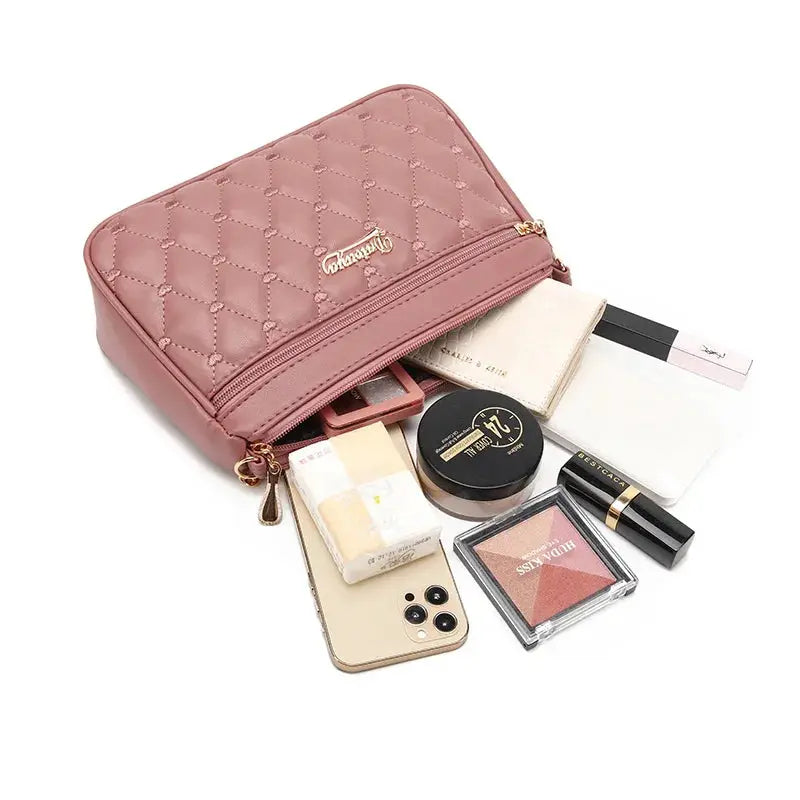 Pink PU leather quilted crossbody bag with gold zipper, large capacity; phone and makeup items around it.