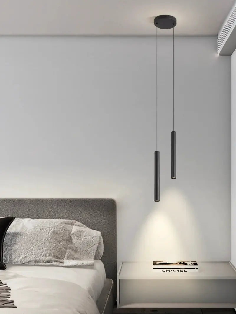 Bedside pendant lamps, two black cylindrical LED fixtures hanging over a nightstand by Simples Market