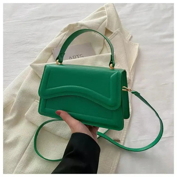 Green PU leather handbag with curved front flap, top handle and crossbody strap