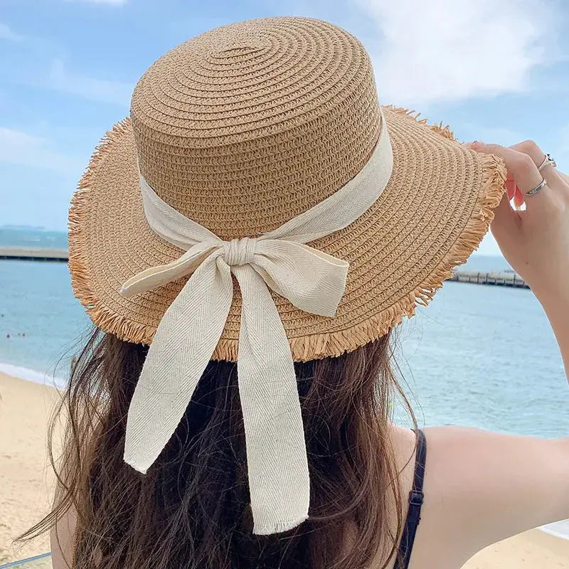 Women's wide-brim straw hat with cream ribbon bow, beach-ready Panama-style.