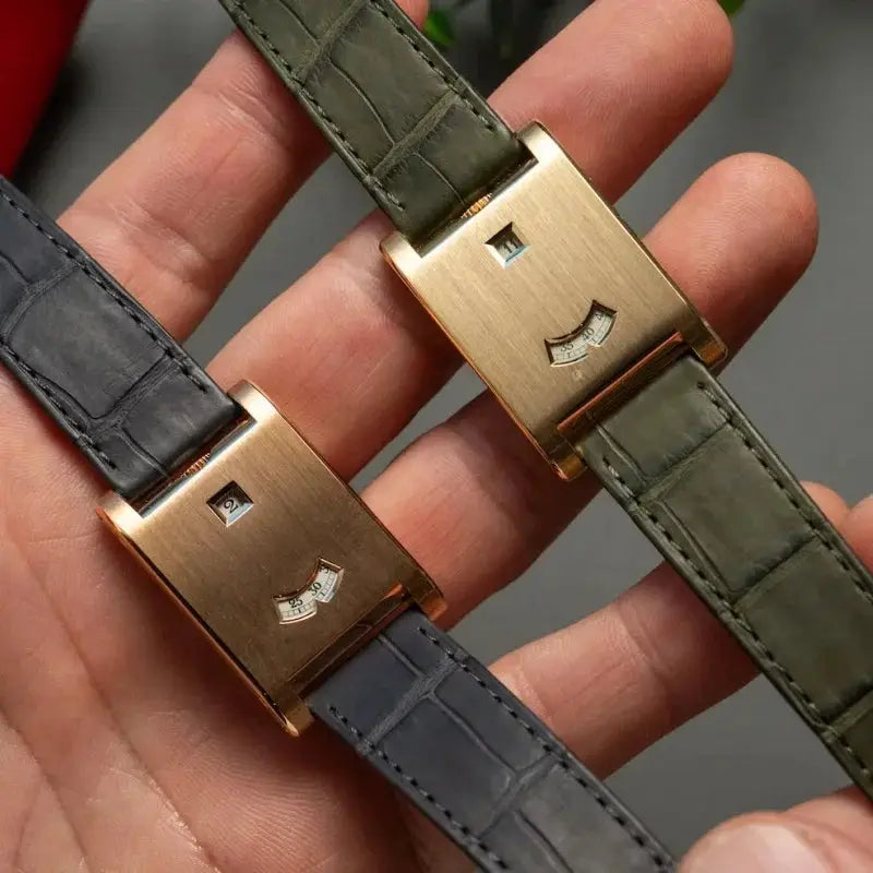 Two men's square watches with gold-tone cases and gray and olive green crocodile-embossed leather straps.