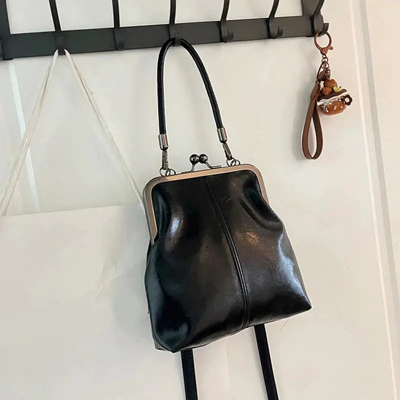 Vintage-style black PU leather handbag with metal frame, top handle and crossbody strap