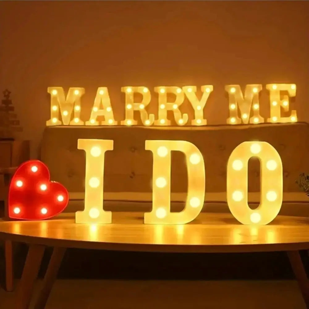 Alphabet LED letter lamp set with warm white glow spelling MARRY ME and IDO, plus a red heart light