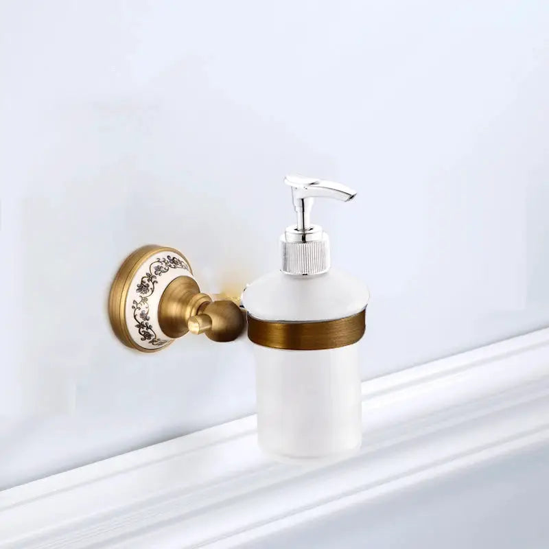 Antique brushed brass wall-mounted soap dispenser with frosted glass bottle and porcelain-accented backplate