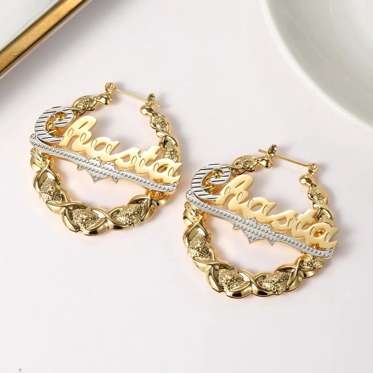 Pair of Qitian XOXO hoop name earrings with gold bamboo-link hoops and a silver rhinestone name bar