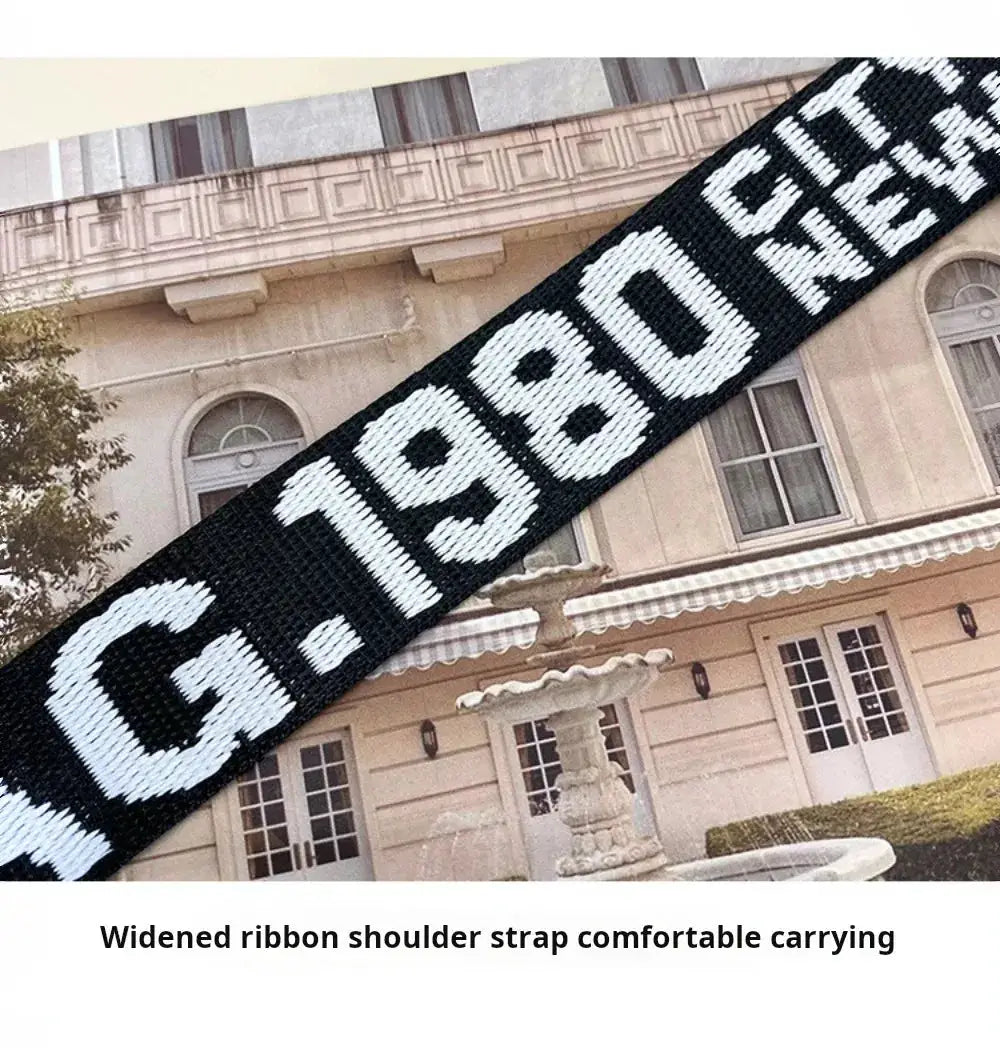 Shoulder bag by Simples Market with a wide black woven strap featuring bold white lettering.
